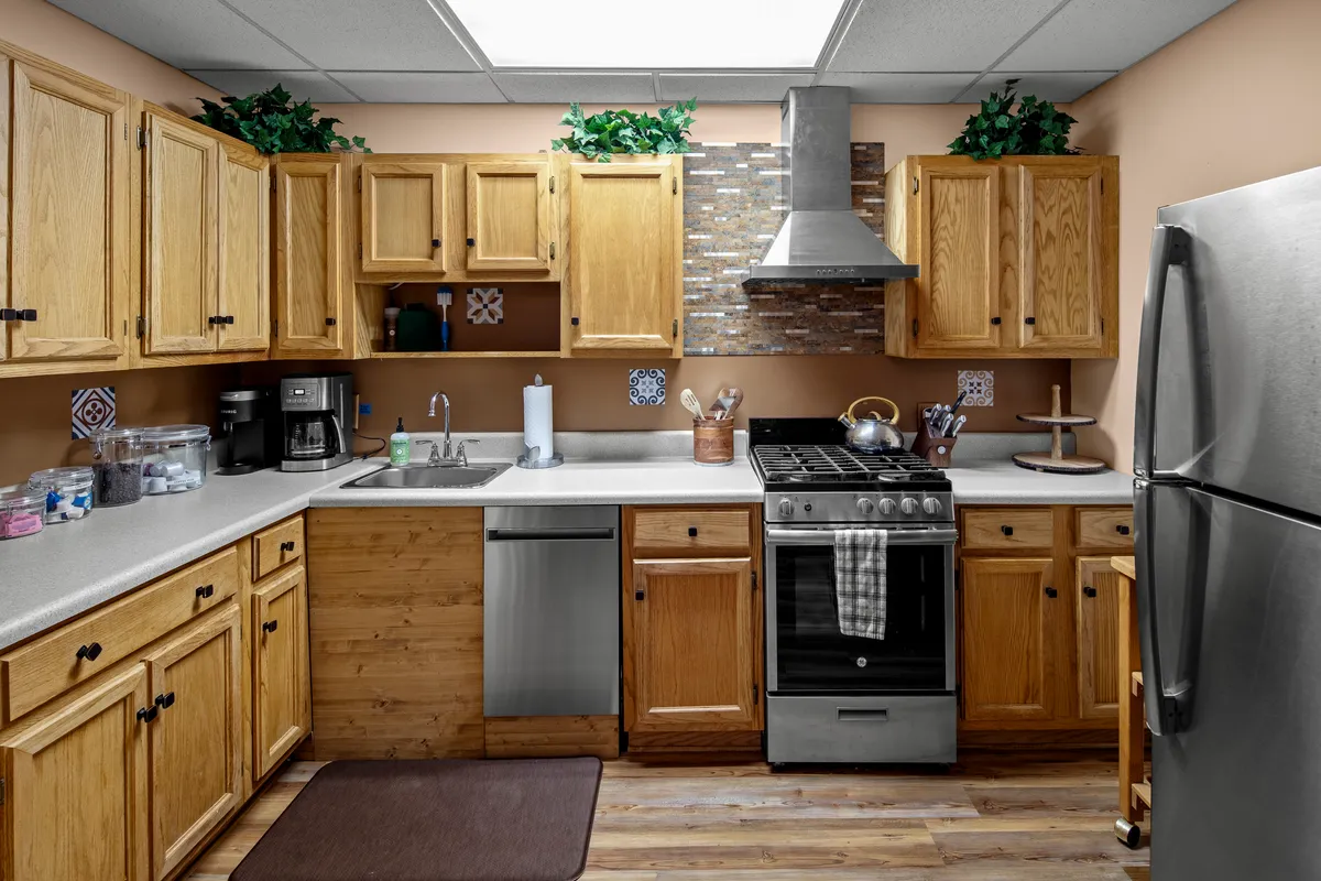 A warm, welcoming kitchen scene with a stainless steel stove, a sink with a sleek faucet, wooden cabinets, and a decorative backsplash. The arrangement invites both cooking and conversation, while the layout supports collaboration and entertaining.